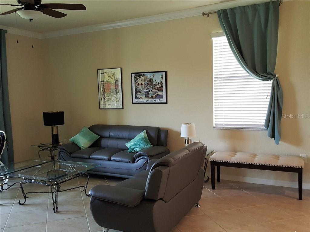 A living room features two gray leather sofas, a glass coffee table, and a bench — 20170 LAGENTE CIRCLE, VENICE, FL