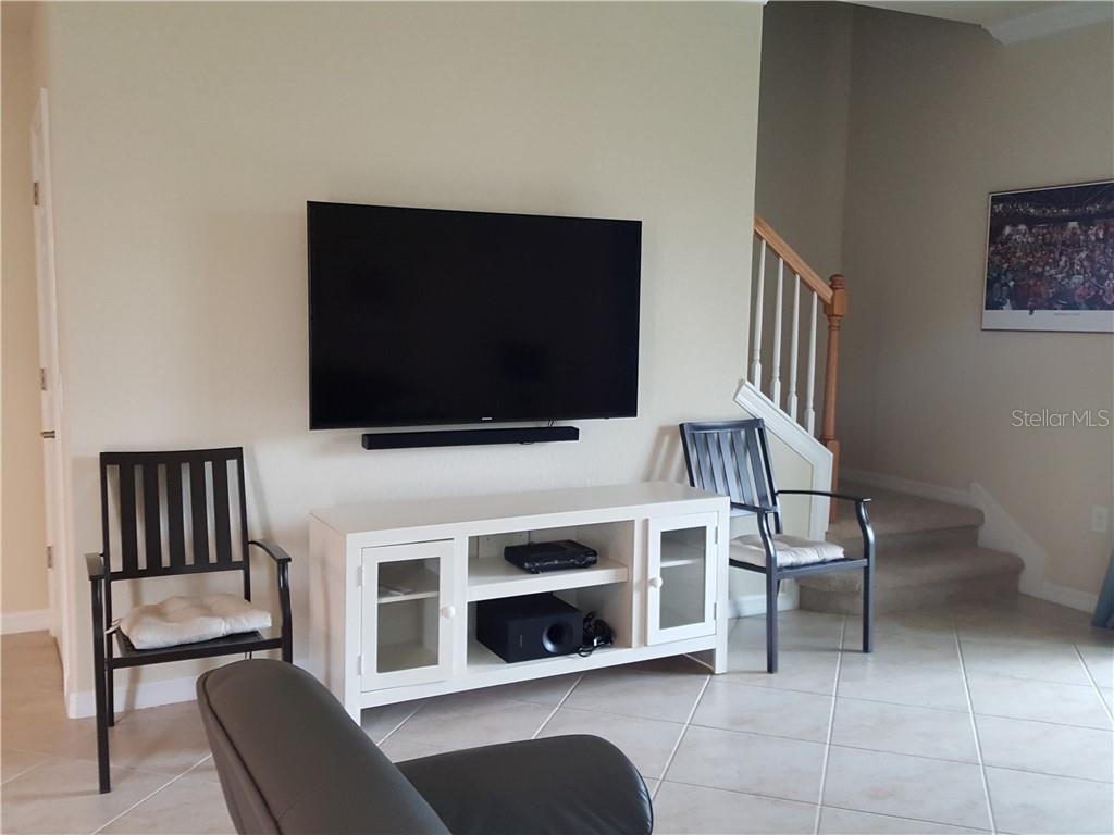 A living room features a wall-mounted television above a white media console and two chairs — 20170 LAGENTE CIRCLE, VENICE, FL