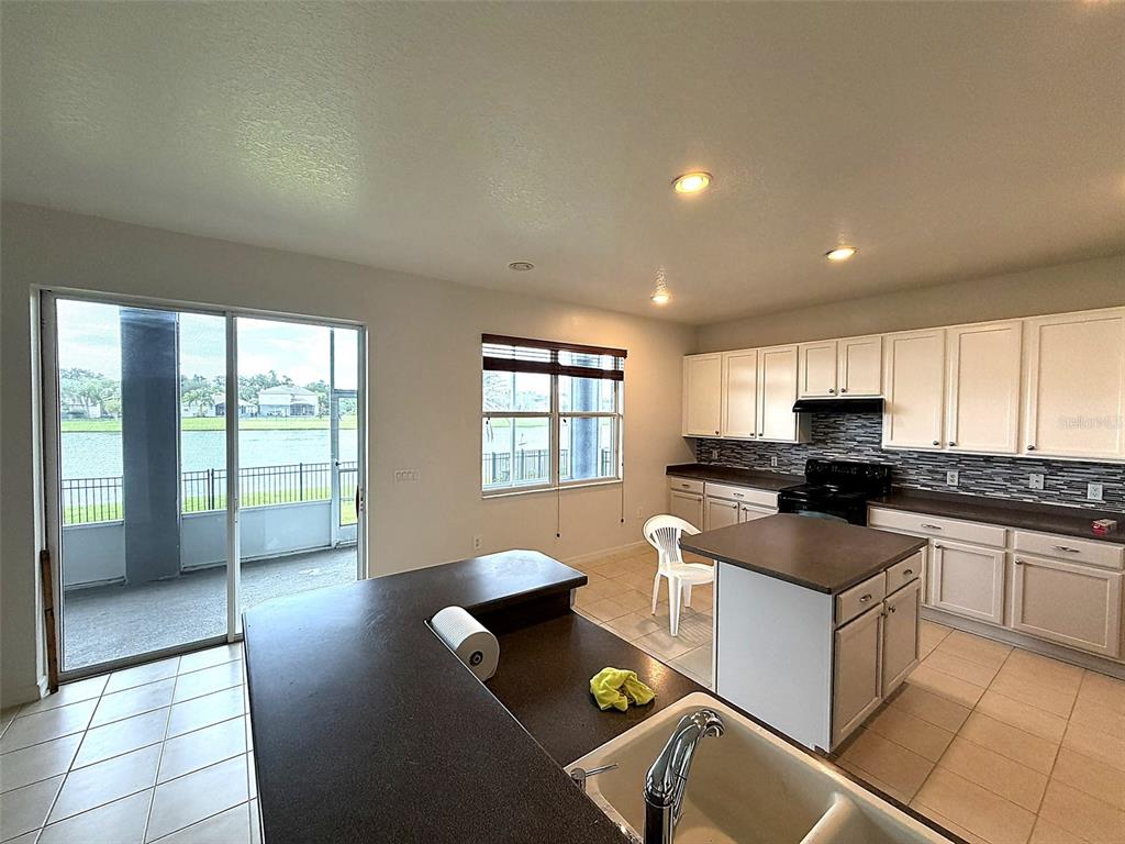 A kitchen with white cabinets, a central island, and a sliding glass door overlooking water — 2549 BALFORN TOWER WAY, WINTER GARDEN, FL