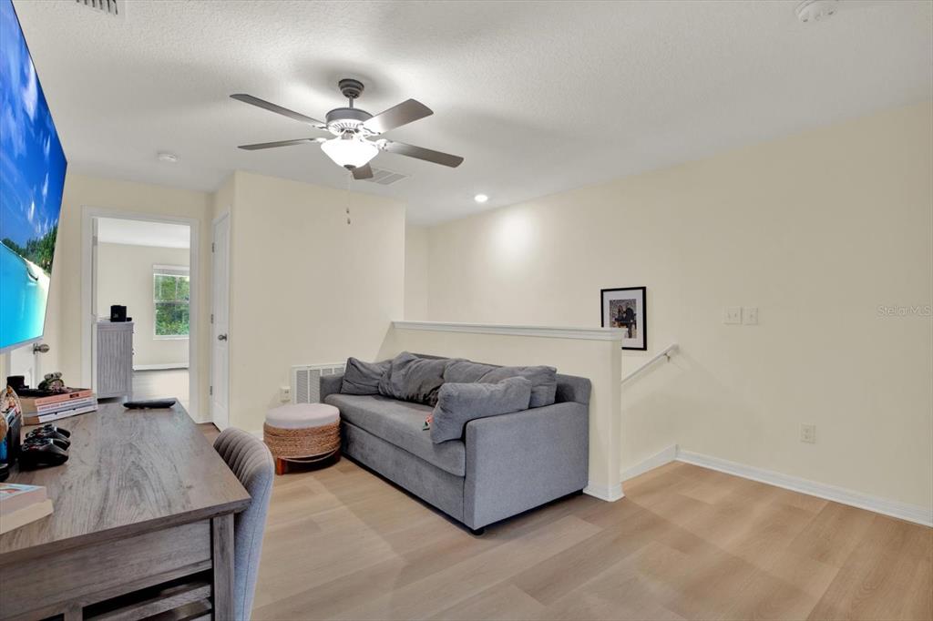 A living area features a gray sofa, a wooden desk, and a ceiling fan — 8538 REEDVILLE STREET, NEW PORT RICHEY, FL