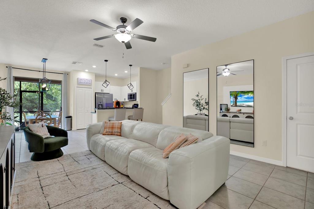 A living room with a white sofa, a green armchair, and two large wall mirrors — 8538 REEDVILLE STREET, NEW PORT RICHEY, FL