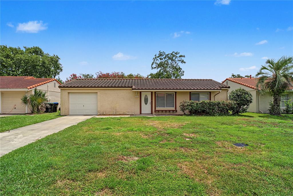A single-story house with a tan exterior, a tiled roof, and a front-facing garage — 10145 BLUFF COURT, ORLANDO, FL