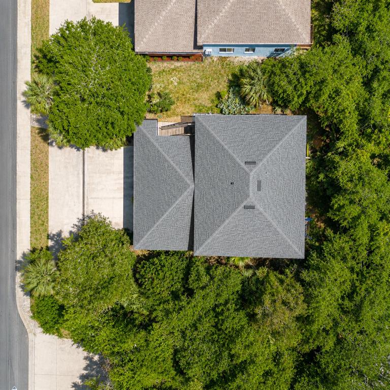 An aerial view shows a house with a gray shingled roof surrounded by trees — 601 E 2ND AVENUE, NEW SMYRNA BEACH, FL