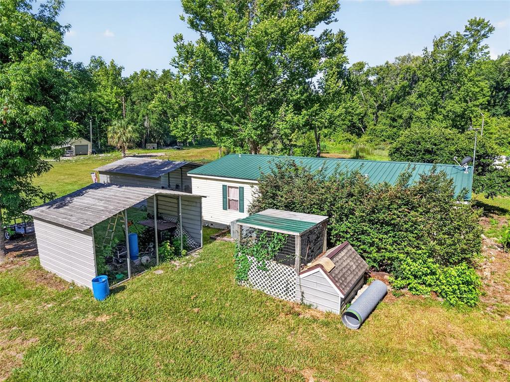 An aerial view shows a house with a green metal roof and several outdoor structures — 24301 JEFFERSON ST, ASTATULA, FL