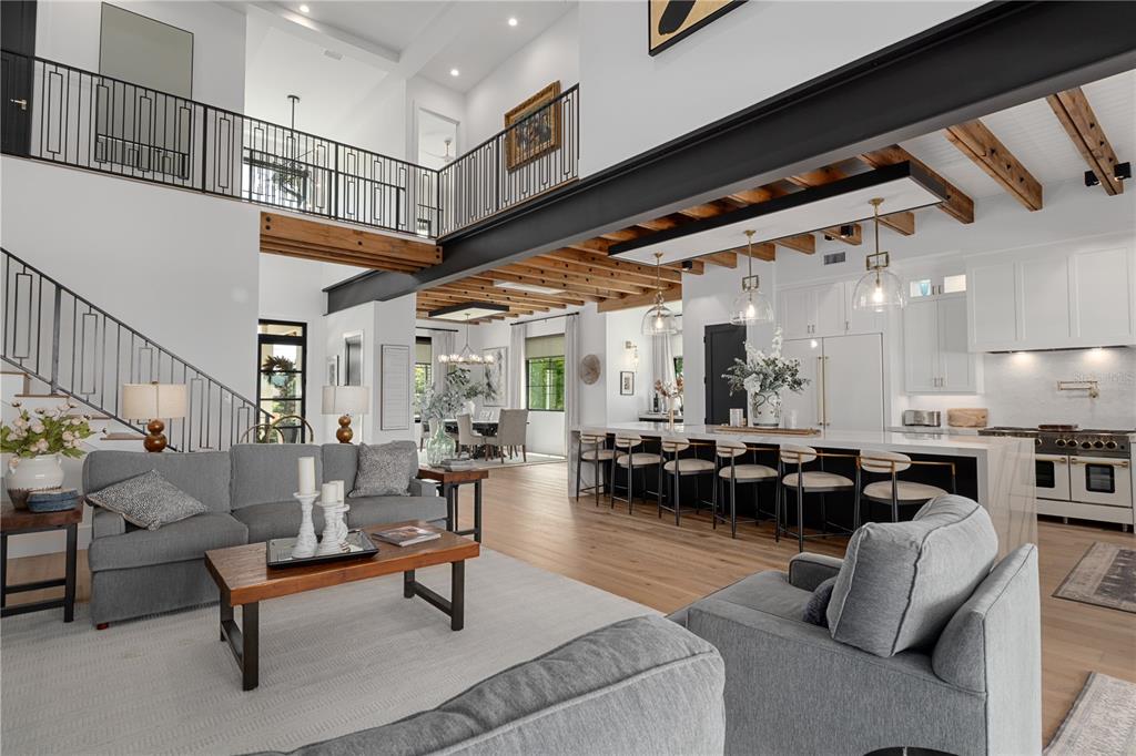 An open-concept living room and kitchen feature a steel beam, wood ceiling, and mezzanine balcony — 692 GLADWIN AVENUE, FERN PARK, FL