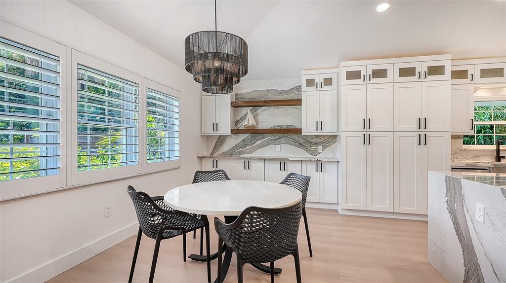 A dining area features a round table, black chairs, a chandelier, and white cabinetry — 3624 S LOCKWOOD RIDGE ROAD, SARASOTA, FL