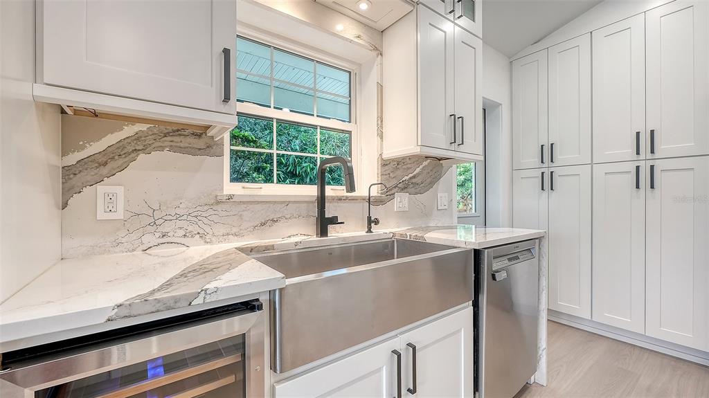 A kitchen features white cabinets, marble-style countertops, a stainless steel farmhouse sink, and a dishwasher — 3624 S LOCKWOOD RIDGE ROAD, SARASOTA, FL