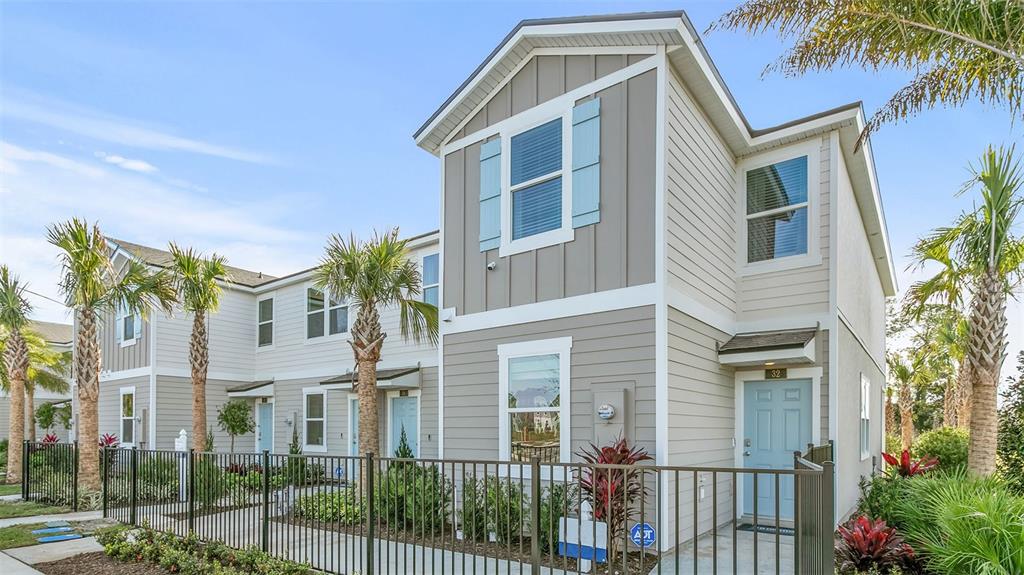 A two-story townhouse exterior features light gray siding, blue shutters, and a front metal fence — 243 PALMETTO RIDGE ROAD, ST AUGUSTINE, FL