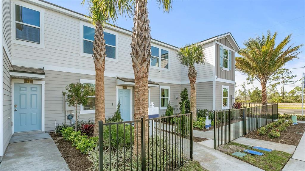 A two-story townhouse exterior with light siding, blue doors, and a black metal fence — 243 PALMETTO RIDGE ROAD, ST AUGUSTINE, FL