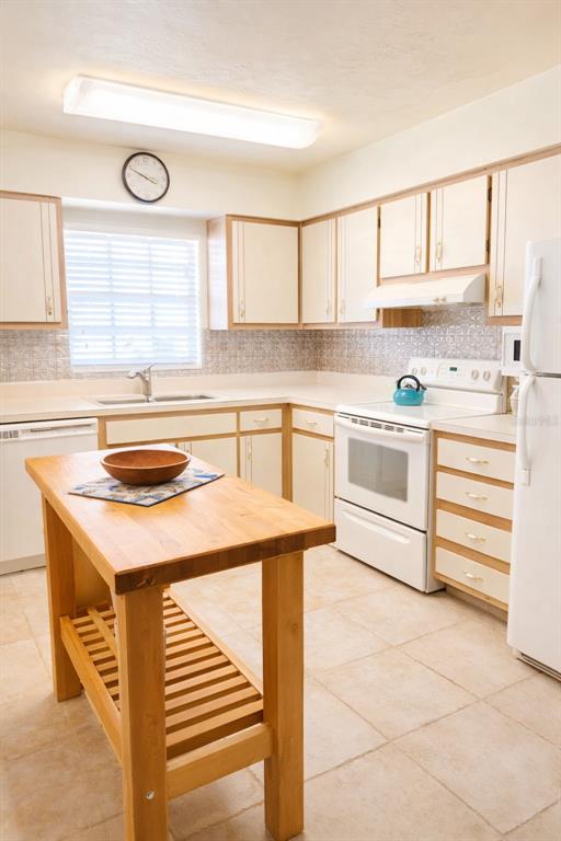 A kitchen features light-colored cabinets, a wooden island, white appliances, and tiled flooring — 1640 JUNO TRAIL UNIT 103F, ASTOR, FL