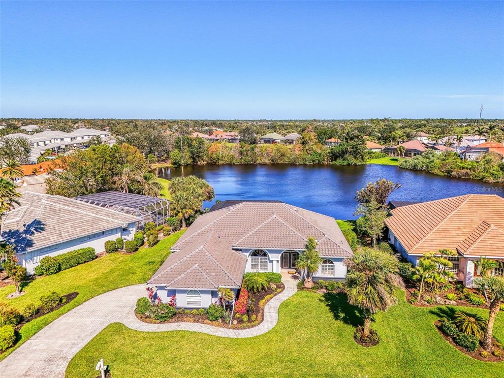 An aerial view of a single-story house with a tiled roof overlooking a lake — 3615 PENNYROYAL ROAD, PORT CHARLOTTE, FL