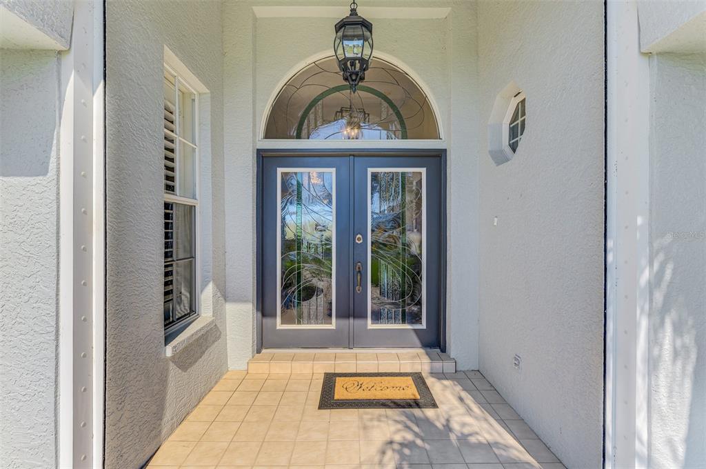 A covered entryway features a tiled floor, a dark double door, and an arched transom window — 3615 PENNYROYAL ROAD, PORT CHARLOTTE, FL