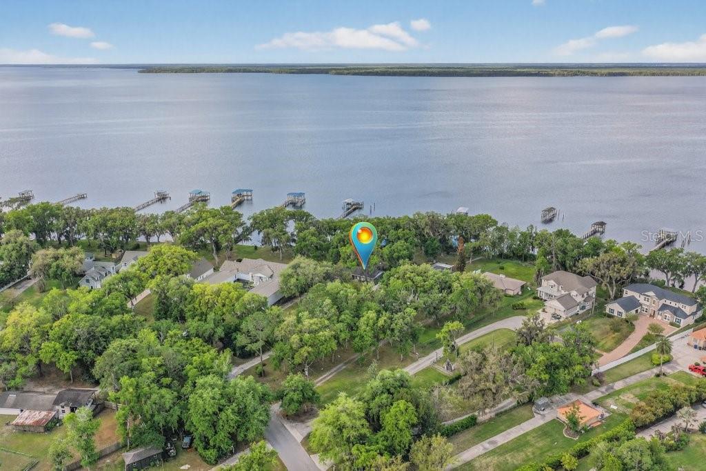 An aerial view shows a house nestled among trees along a large lakefront property — 6373 JACK WRIGHT ISLAND ROAD, ST AUGUSTINE, FL
