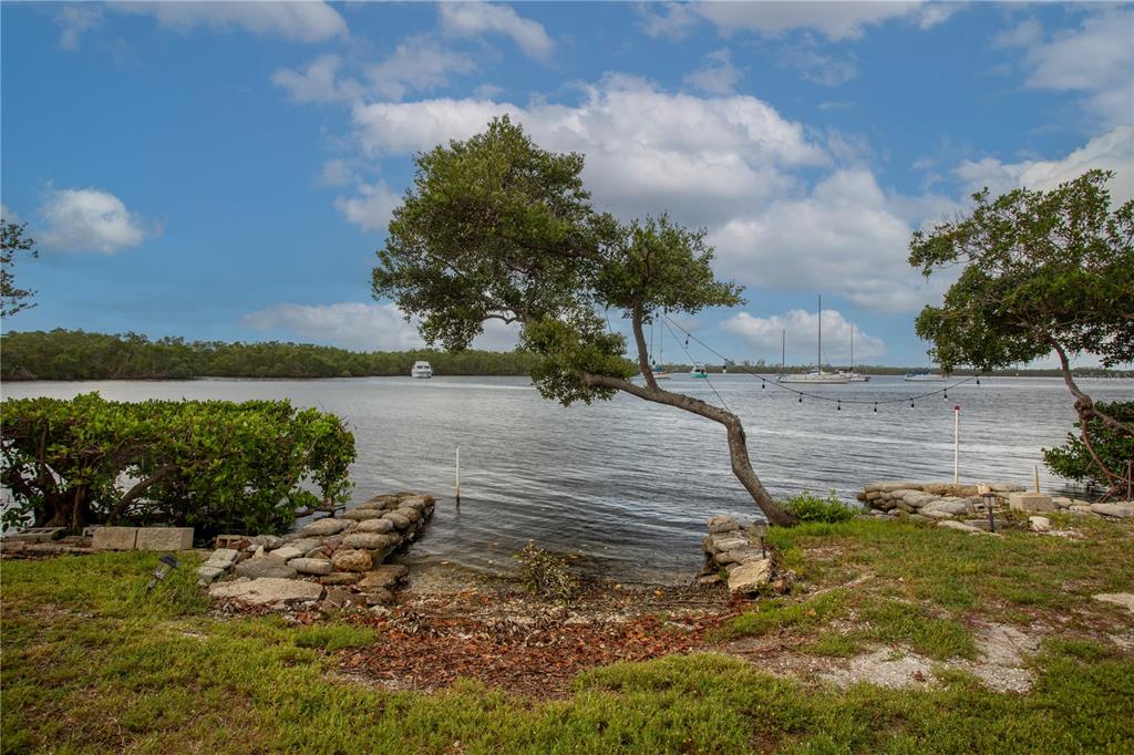 A leaning tree stands over a small stone-lined boat launch on a calm waterfront — 3312 W SHELL POINT ROAD, RUSKIN, FL
