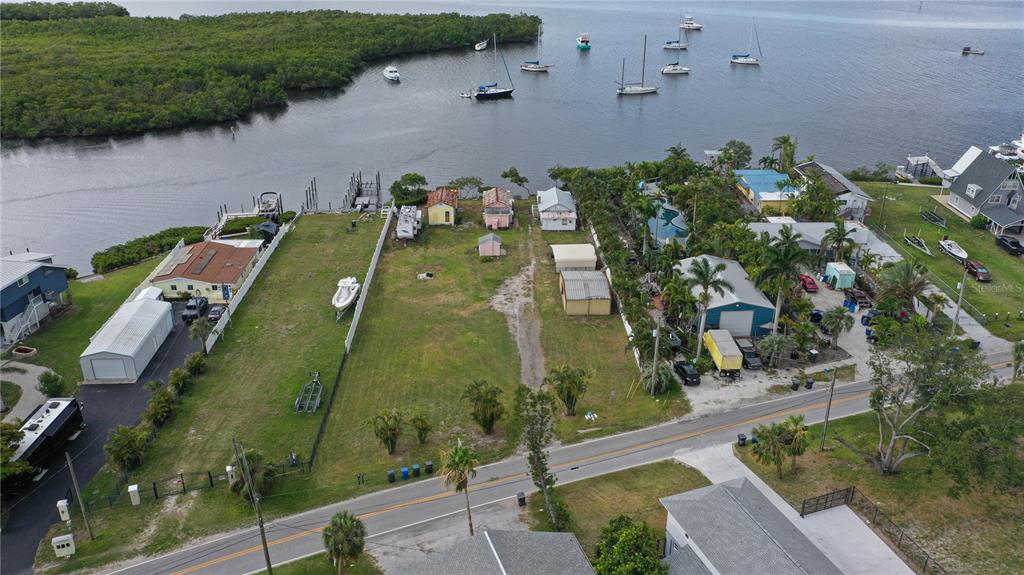 An aerial view shows a waterfront lot with several small structures and boats docked nearby — 3312 W SHELL POINT ROAD, RUSKIN, FL