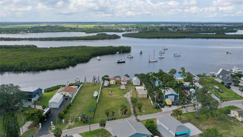 An aerial view shows waterfront properties with boat docks, grassy lots, and moored sailboats — 3312 W SHELL POINT ROAD, RUSKIN, FL