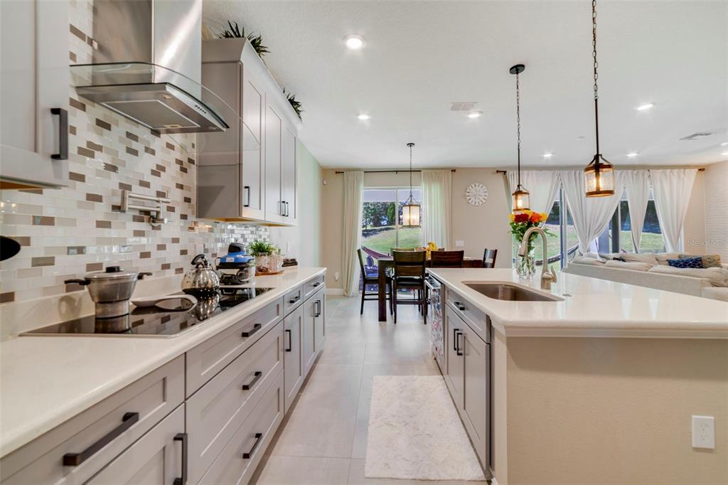A modern kitchen features gray cabinetry, white countertops, a tile backsplash, and a center island — 1970 STANDING ROCK CIRCLE, OAKLAND, FL