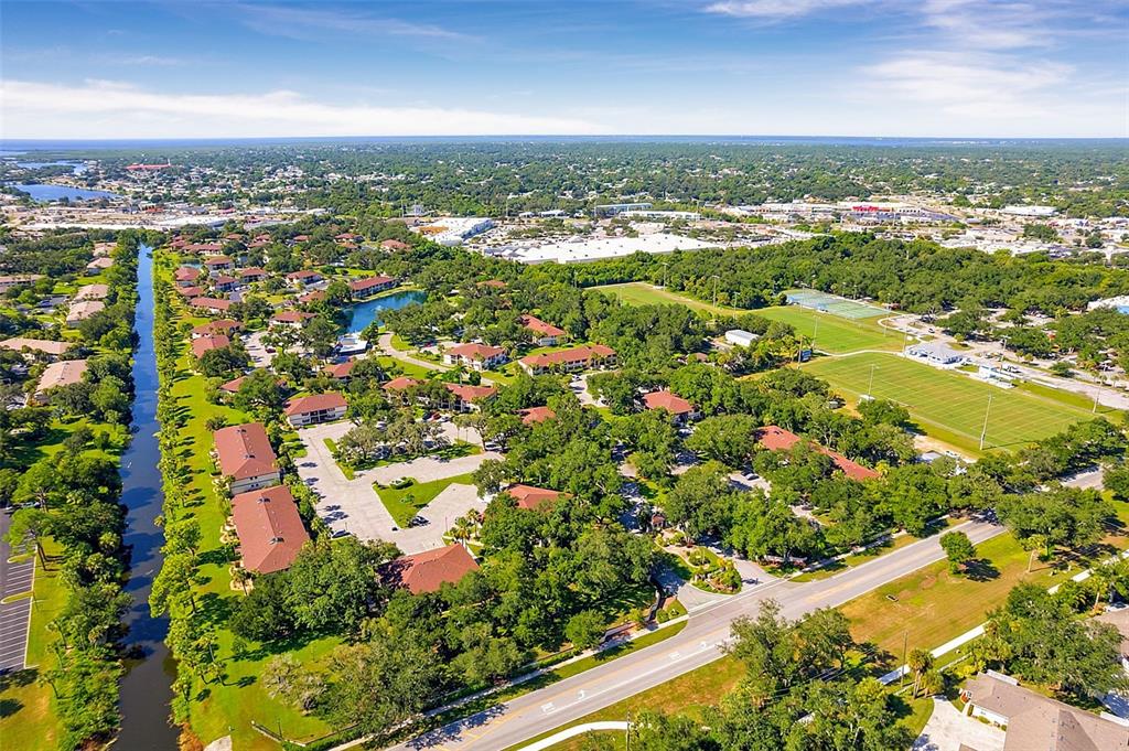 An aerial view shows a residential apartment complex with a canal and nearby sports fields — 19505 QUESADA AVENUE UNIT A208, PORT CHARLOTTE, FL