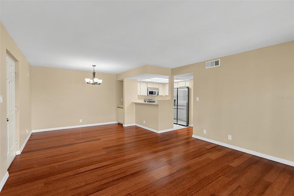 An open-concept dining area and kitchen featuring hardwood floors and neutral-toned walls — 19505 QUESADA AVENUE UNIT A208, PORT CHARLOTTE, FL
