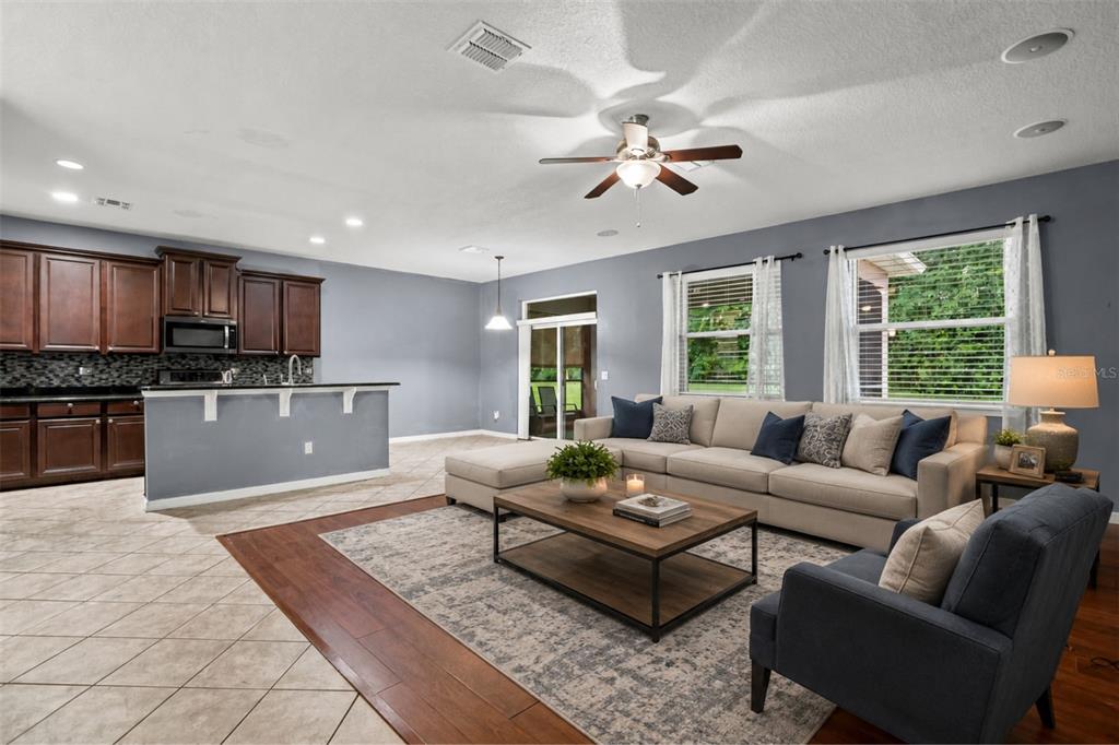 An open-concept living room and kitchen with tile and wood flooring, neutral furniture, and windows — 925 COUNTS CREST CIRCLE, APOPKA, FL