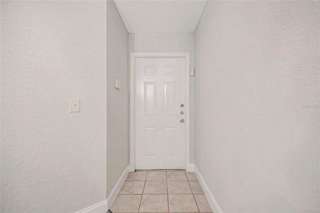 A three-story apartment building with screened balconies and a central recessed stairwell entrance — 7511 SEURAT STREET UNIT 10102, ORLANDO, FL