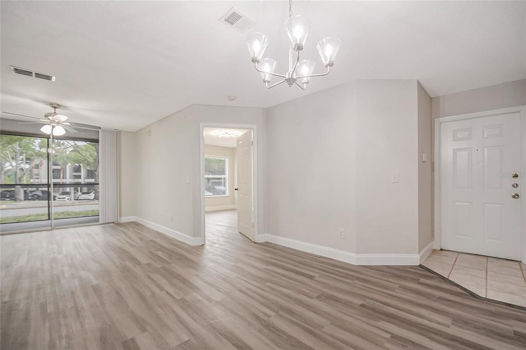 An open-concept living and dining area features light wood-look flooring and a breakfast bar — 7511 SEURAT STREET UNIT 10102, ORLANDO, FL