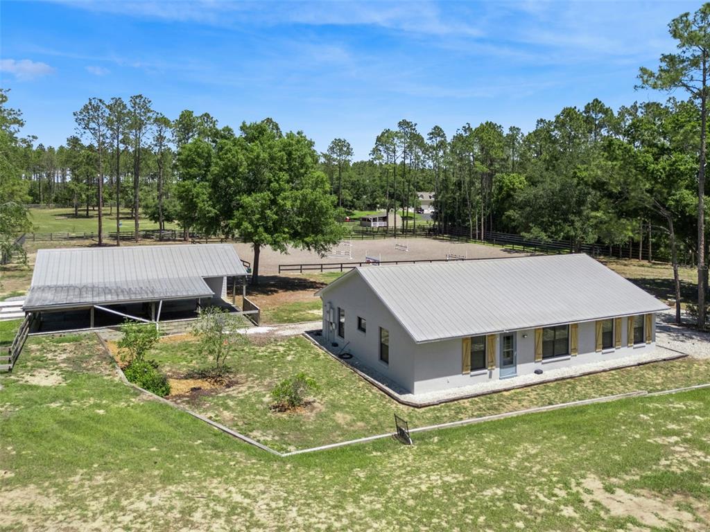 An aerial view shows a house, a detached barn, and a fenced riding arena outdoors — 20701 COUNTY ROAD 44A, EUSTIS, FL