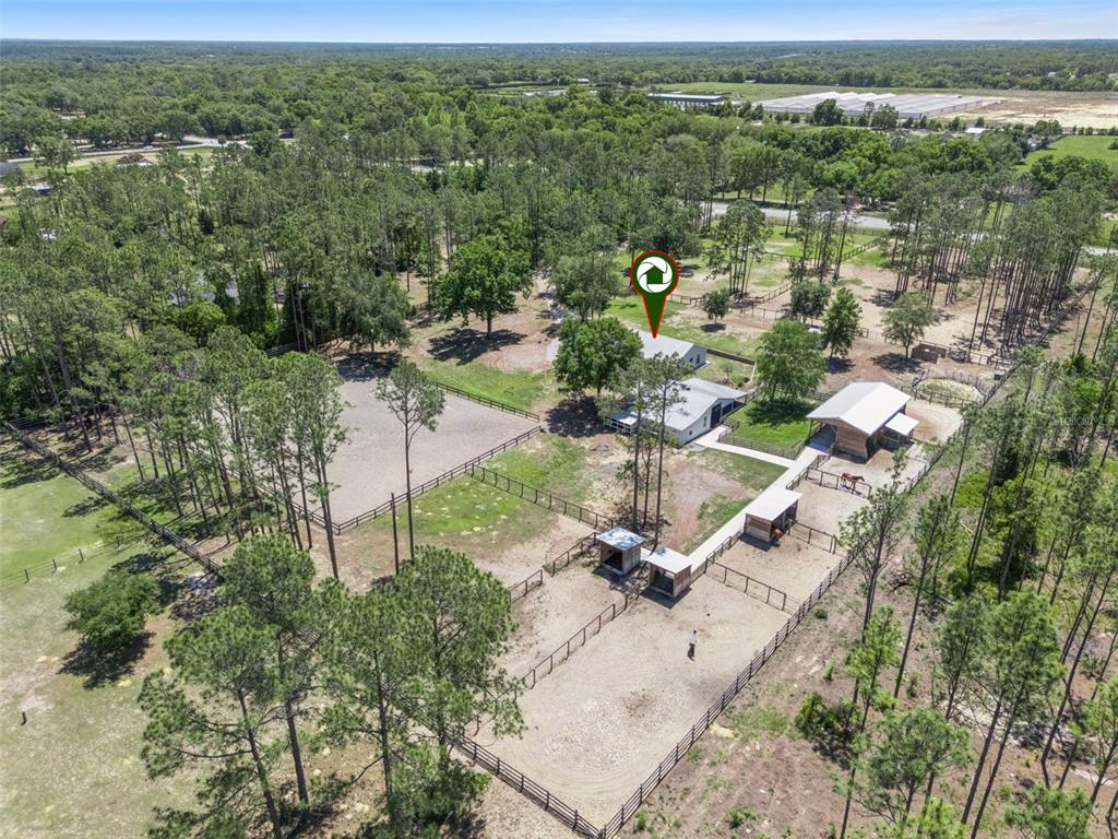 An aerial view shows a rural property with a house, horse stables, and fenced paddocks — 20701 COUNTY ROAD 44A, EUSTIS, FL