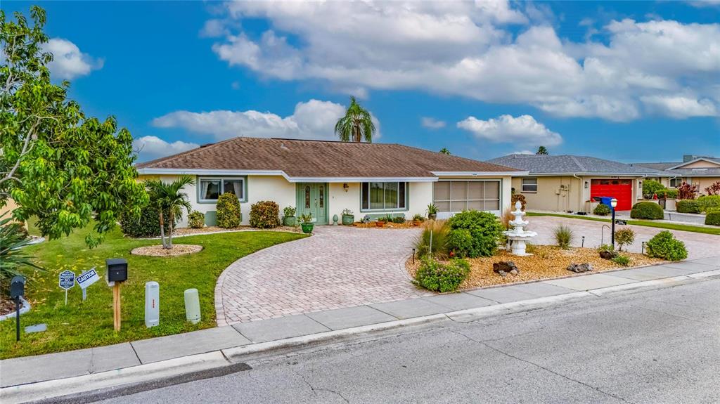 A single-story house with a paved driveway, a front lawn, and a white fountain — 1516 NEW BEDFORD DRIVE, SUN CITY CENTER, FL