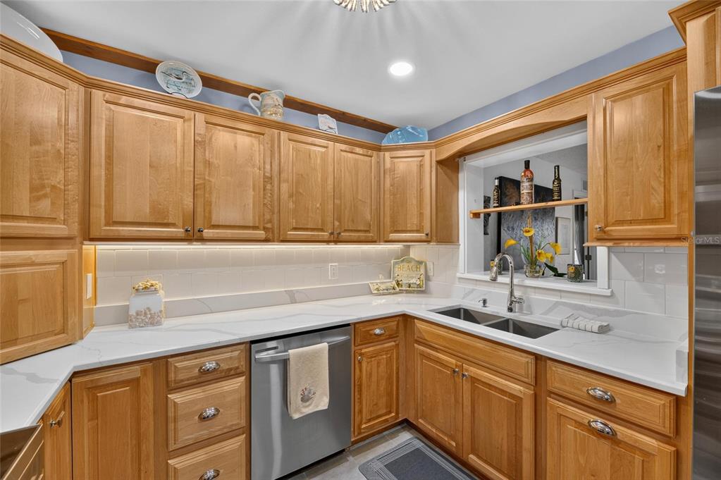 A kitchen with light wood cabinets, white countertops, a stainless steel dishwasher, and a sink — 1516 NEW BEDFORD DRIVE, SUN CITY CENTER, FL