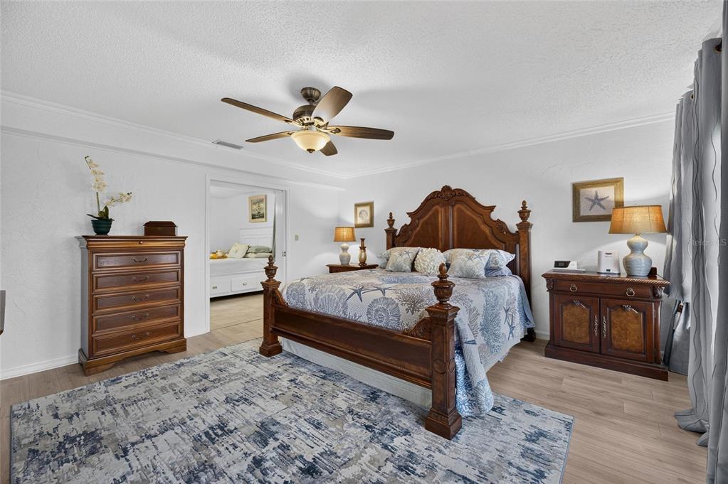 A bedroom features a wooden bed frame, a tall dresser, and a ceiling fan — 1516 NEW BEDFORD DRIVE, SUN CITY CENTER, FL