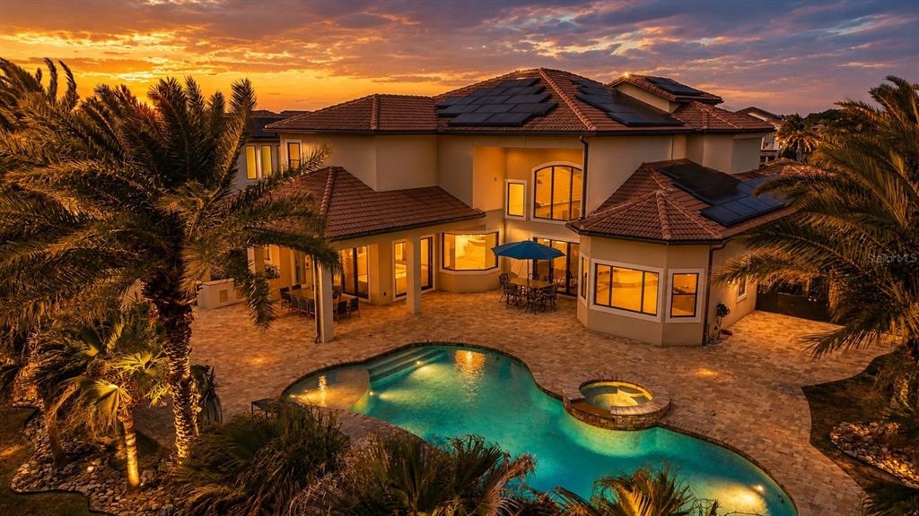 An aerial view of a two-story house with a pool, patio, and solar panels at sunset — 4303 ISABELLA CIRCLE, WINDERMERE, FL