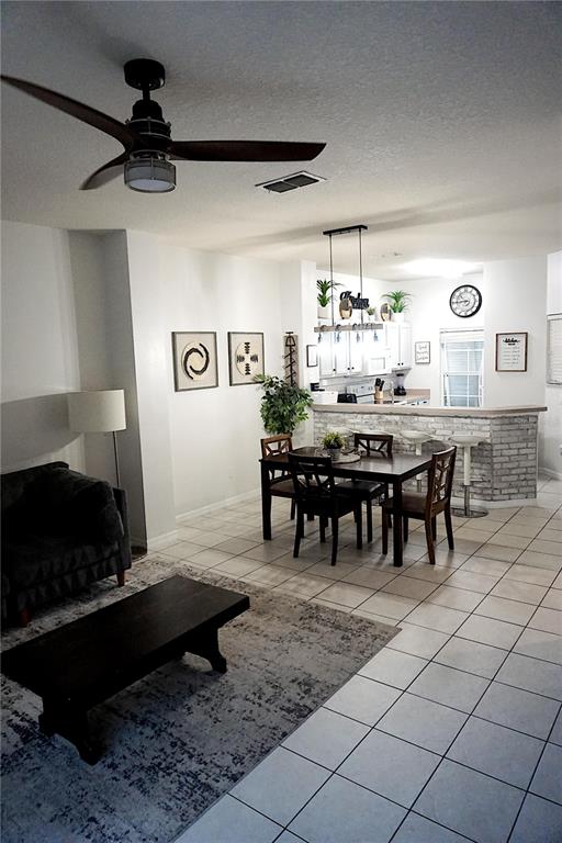 An open-concept living and dining area features tile flooring, a ceiling fan, and a kitchen — 8529 BAY LILLY LOOP, KISSIMMEE, FL