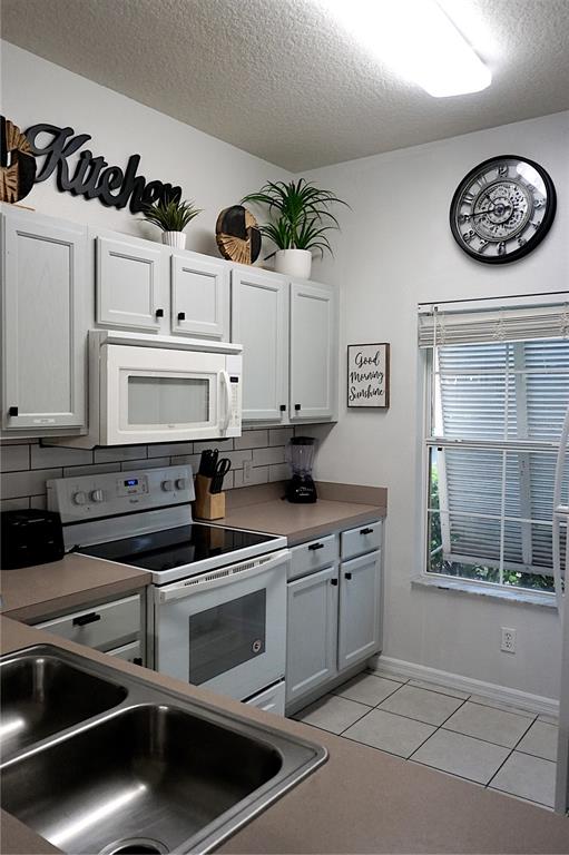 A kitchen features light gray cabinets, white appliances, a double sink, and a wall clock — 8529 BAY LILLY LOOP, KISSIMMEE, FL