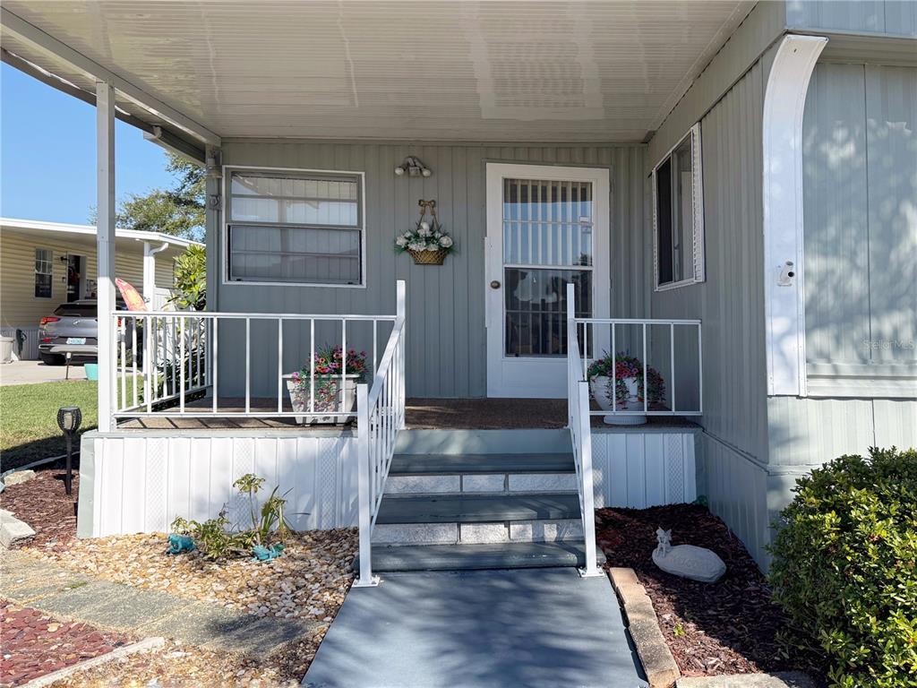 The exterior of a mobile home features a covered porch with white railings and stairs — 123 SAINT KITTS WAY, APOLLO BEACH, FL