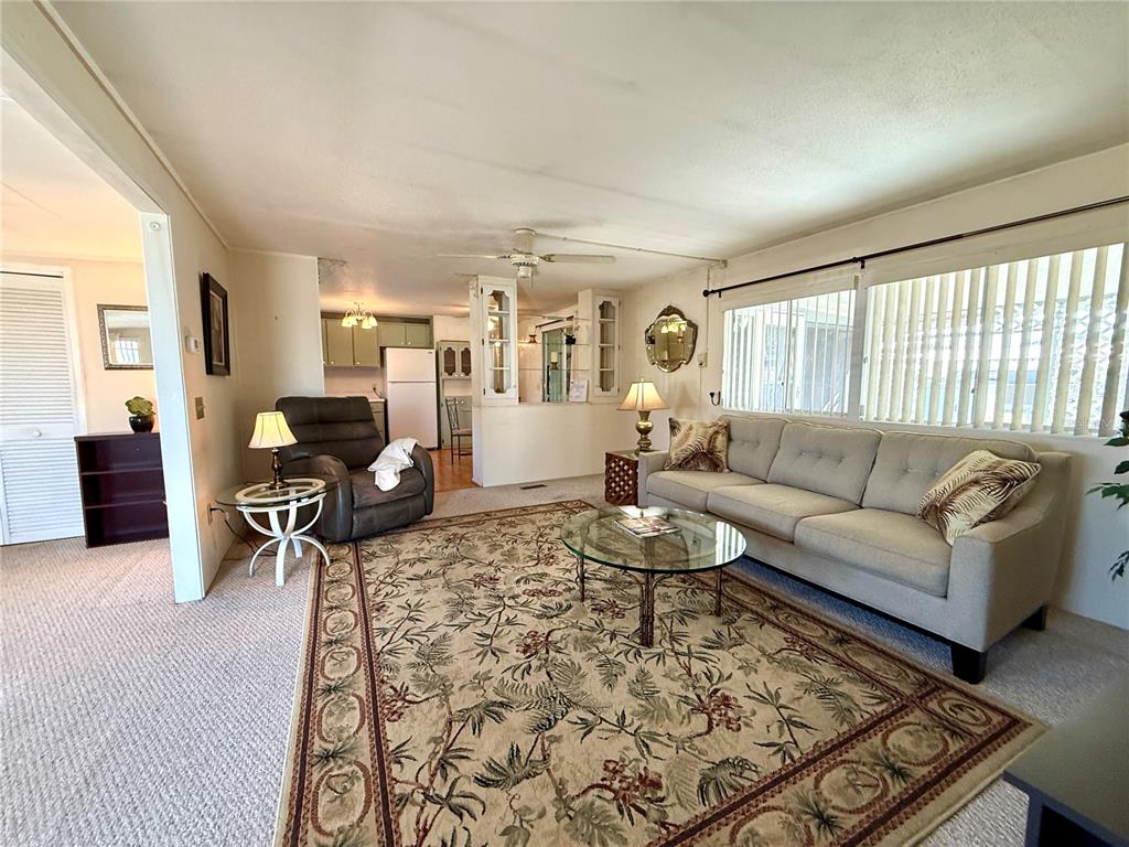 A living room with a beige sofa, patterned area rug, and an open kitchen beyond — 123 SAINT KITTS WAY, APOLLO BEACH, FL