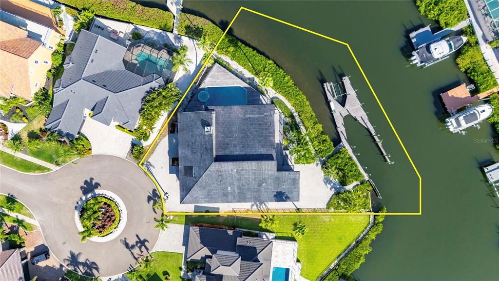 An aerial view shows a waterfront house with a pool, dock, and surrounding landscaping — 903 CAPRICCIO LANE, APOLLO BEACH, FL