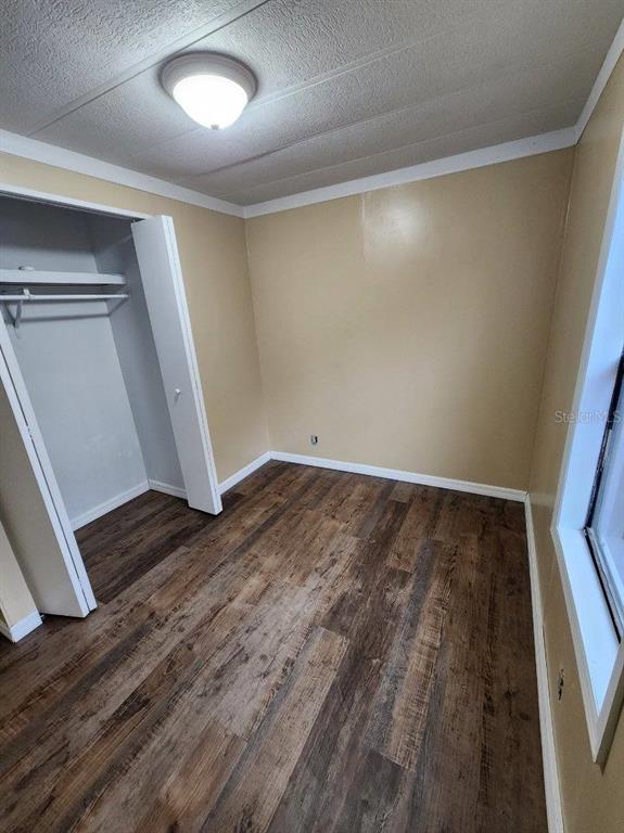 An empty bedroom features light tan walls, wood-look laminate flooring, and a white closet — 5010, 5040, 5080, & 5120 S BARKER POINT, LECANTO, FL