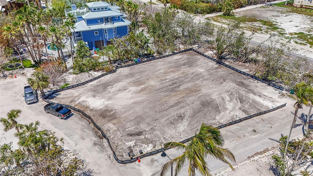 An aerial view shows a cleared, fenced-in residential lot next to a blue house — 6605 GULFSIDE ROAD, LONGBOAT KEY, FL