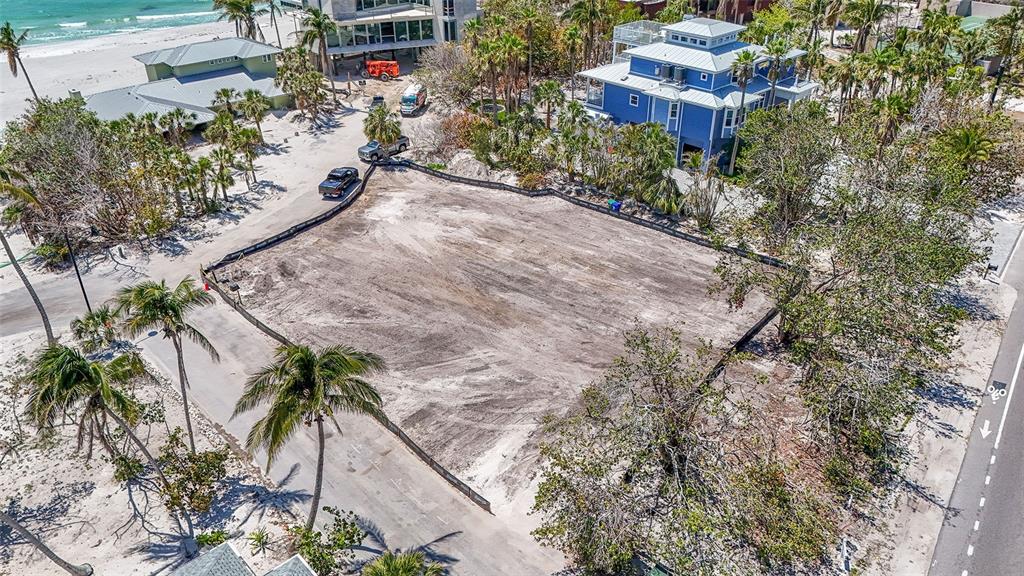 An aerial view shows a cleared, fenced-in rectangular lot near a beach and houses — 6605 GULFSIDE ROAD, LONGBOAT KEY, FL