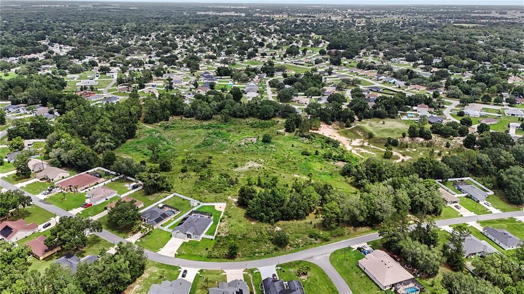 An aerial view shows a large, undeveloped grassy lot surrounded by suburban residential houses — 11303 SW 62ND CIRCLE, OCALA, FL
