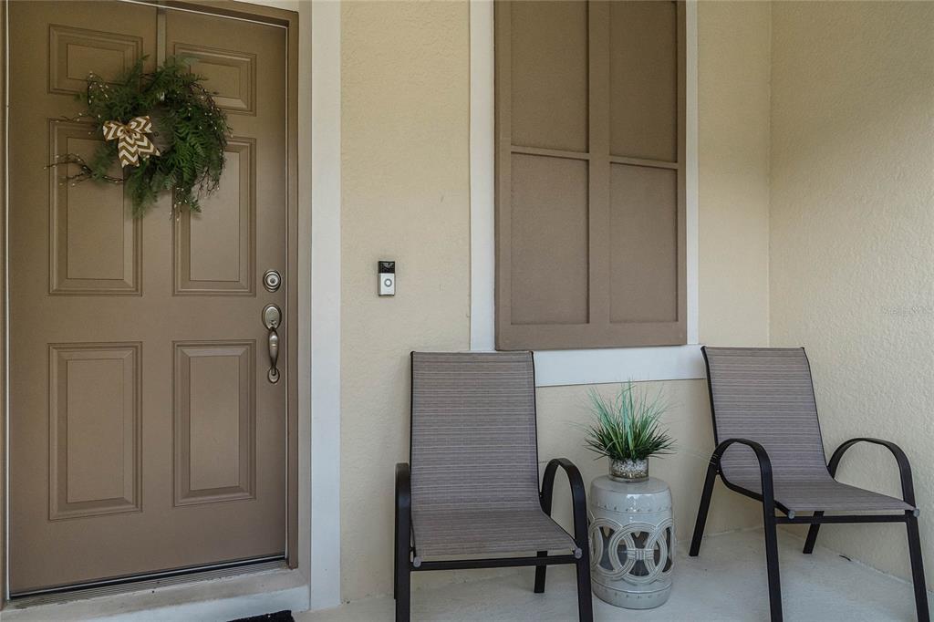 A front porch features a brown door with a wreath, two chairs, and a side table — 610 FORTANINI CIRCLE, OCOEE, FL