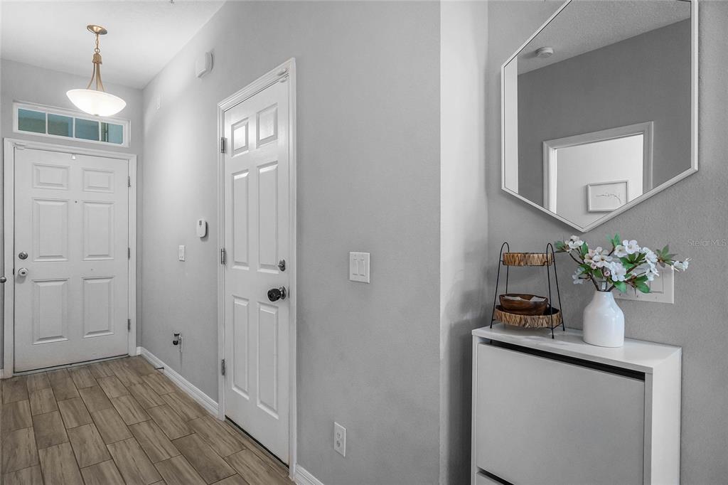 An entryway features a white front door, a closet door, tile flooring, and a wall mirror — 610 FORTANINI CIRCLE, OCOEE, FL