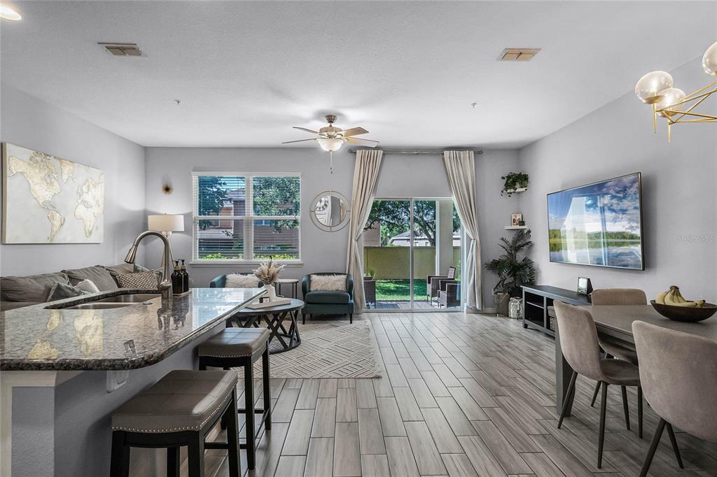 An open-concept living and dining area features tile flooring, a kitchen island, and sliding doors — 610 FORTANINI CIRCLE, OCOEE, FL