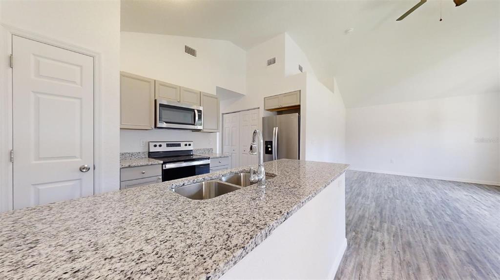A kitchen with granite countertops, stainless steel appliances, and light gray cabinets — 13725 SW 111TH LANE, DUNNELLON, FL