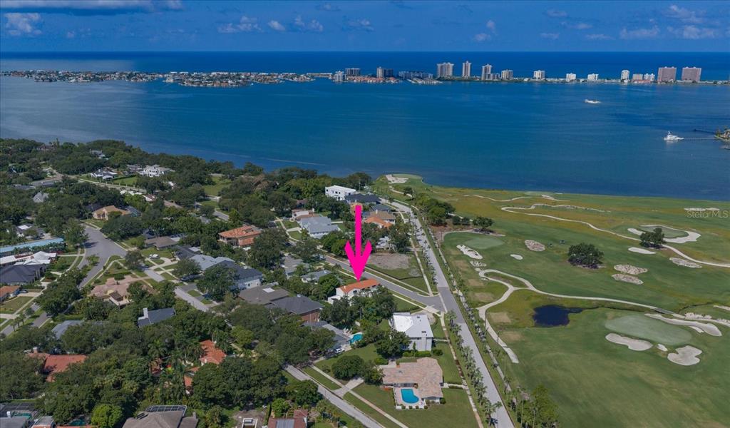 An aerial view shows a residential neighborhood bordering a golf course and a large bay — 561 PALMETTO ROAD, BELLEAIR, FL