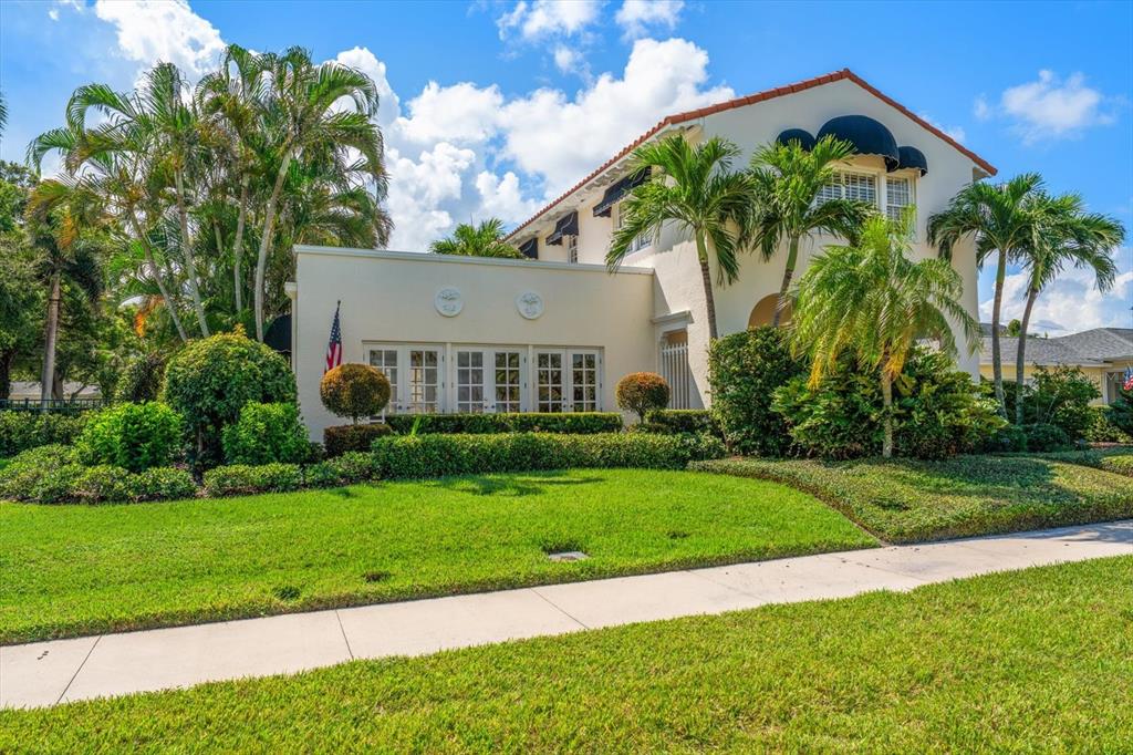 A two-story stucco house with a tile roof, palm trees, and a manicured lawn — 561 PALMETTO ROAD, BELLEAIR, FL