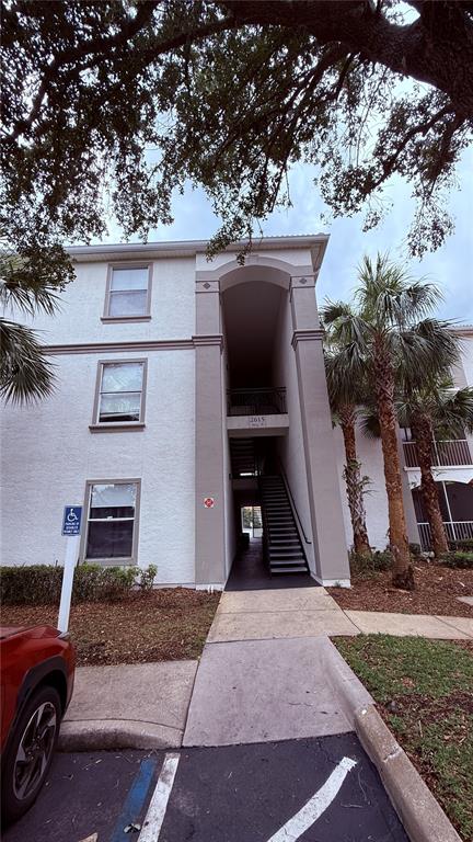 An exterior view of a multi-story apartment building with a central staircase and palm trees — 2615 MAITLAND CROSSING WAY UNIT 204, ORLANDO, FL