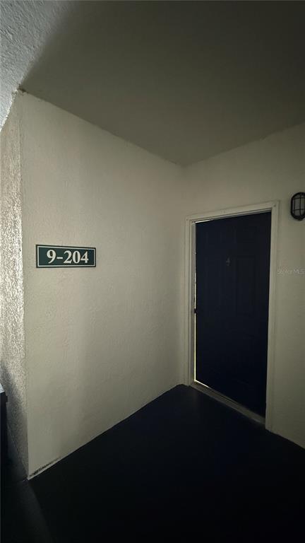 A dark front door is set into a plain white wall with a unit number sign — 2615 MAITLAND CROSSING WAY UNIT 204, ORLANDO, FL