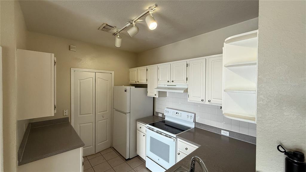 A kitchen features white cabinets, white appliances, brown countertops, and a track lighting fixture — 2615 MAITLAND CROSSING WAY UNIT 204, ORLANDO, FL